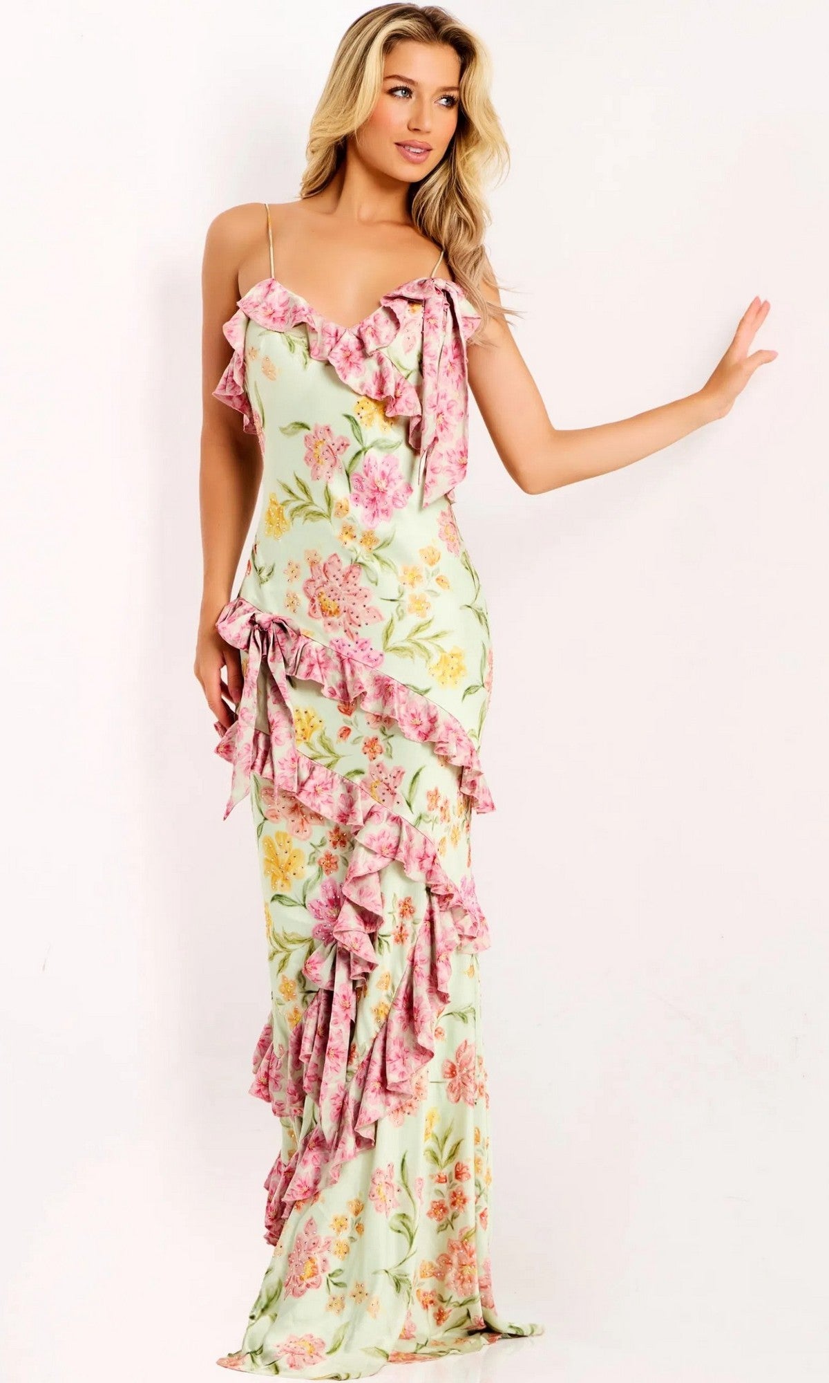 A woman models the Jovani 47236 Ruffled Long Floral-Print Prom Gown in multi, featuring thin straps and ruffles, against a plain light background.